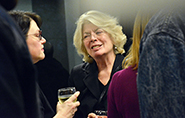 Closeup of two people mingling at a reception, facing one another and holding beverages.