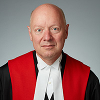 Justice Geoffrey B. Gomery wearing black, red, and white judicial robe
