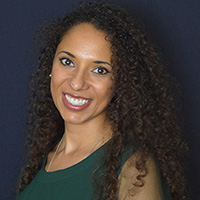 Alexis McGee smiling wearing an emerald green top, in front of a navy blue studio background