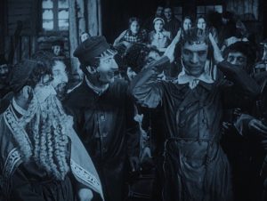 Still from Das alte Gesetz (The Ancient Law), 1923. A merry crowd of people watching someone donning a crown.